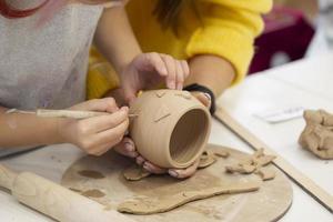 The child's hands make a clay cup. Master class on making clay products. photo