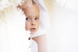 A handsome little boy peeps out. The big eyes of the child look into the camera. photo