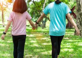 Two sister holding hands in the park in warm spring day. Happy friendship family concept. photo