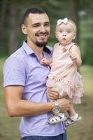 retrato de un contento papá jugando con su pequeño hija para un caminar. paternidad. foto