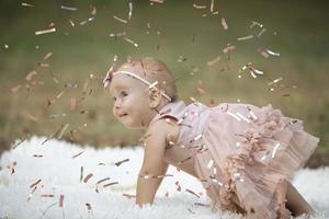 A funny little girl in a bright confetti. Child celebrates one year. Beautiful baby. photo