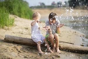 Water splashes are flying at children playing on the river bank. photo