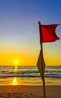 rojo bandera nadando prohibido alto olas con puesta de sol en México. foto