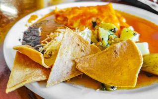 Mexican omelet eggs black beans potatoes nachos on white plate. photo