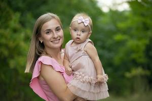 contento mujer sostiene un año de edad hija en su brazos. maternidad. foto