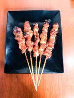 There are five skewers of blushing spicy chicken photo