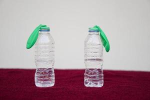 Green flat balloons on top of transparent test bottles. Concept, science experiment about reaction of chemical substance, vinegar and baking soda that cause balloon inflat.  First  step of experiment photo