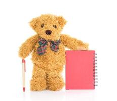 Teddy bear with pen on blank red notebook photo