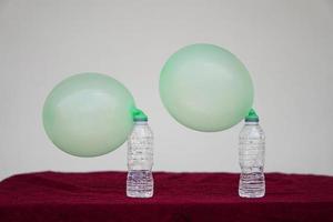 Green inflated balloons on top of transparent test bottles. Concept, science experiment about reaction of chemical substance, vinegar and baking soda that cause balloon inflat. Last step of experiment photo