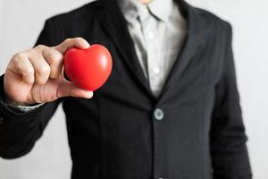 empresario en traje participación rojo corazón, cuidado de la salud, dando amar, enamorado y amor festival concepto foto