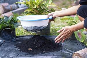 preparación de una mezcla de suelo a partir de compost fértil, humus y vermiculita en el suelo de una bolsa de basura negra en el jardín. mezclar los componentes del suelo para la preparación del sustrato para trasplantar plantas. foto