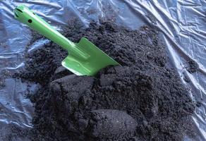 preparación de una mezcla de suelo a partir de compost fértil, humus y vermiculita en el suelo de una bolsa de basura negra en el jardín. mezclar los componentes del suelo para la preparación del sustrato para trasplantar plantas. foto