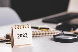 Small 2023 year calendar on desk with financial management background. concept of planning and goals for financial management and business growth photo