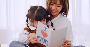 A little daughter giving mom handmade greeting card and wishing her Happy Mother's Day. photo