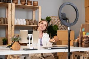 A young pretty woman entrepreneur live streaming to sale craft products  to customers in her shop , Technology online business concept. photo