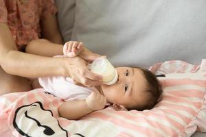 un bebé niña es Bebiendo Leche botella, familia, niño, infancia y paternidad concepto foto