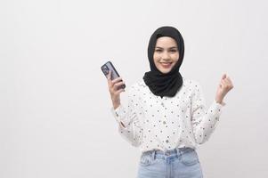 Beautiful musllim woman with hijab using smartphone over white background, technology concept. photo