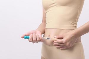 Close up woman using IVF treatment injection on belly to prepare reproductive fertility , Ovulation stimulation . photo