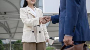 Asian senior mature middle aged businessman handshaking young businesswoman in modern city photo