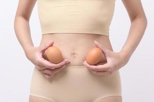 Close up woman holding eggs on belly , prepare reproductive fertility , Ovulation stimulation , matherinty concept photo