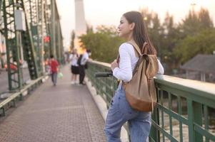 retrato de joven hermosa mujer con un eléctrico scooter terminado puente en moderno ciudad antecedentes foto