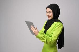 Beautiful musllim woman with hijab using tablet over white background, technology concept. photo