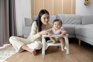 Young mother helping baby eating blend food on baby chair photo