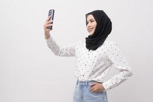 Beautiful musllim woman with hijab using smartphone over white background, technology concept. photo