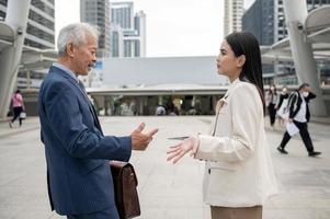 Asian senior mature middle aged businessman and young businesswoman having an argument in modern city photo