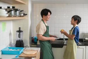 Happy smiling Young Asian father and son washing dishes in kitchen at home photo