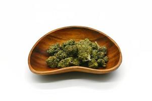 Marijuana buds in a wooden bowl isolated on a white background photo