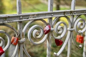 Colourful love locks on an old railing of a small bridge photo