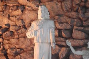 estatua de señor Jesús en pie con un antecedentes de rocas fijo en el pared foto