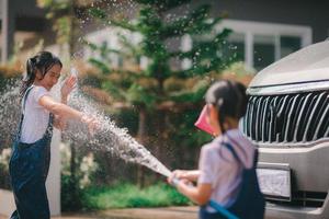 Sibling Asian girls wash their cars and have fun playing indoors on a hot summer day.