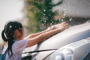 Sibling Asian girls wash their cars and have fun playing indoors on a hot summer day. photo