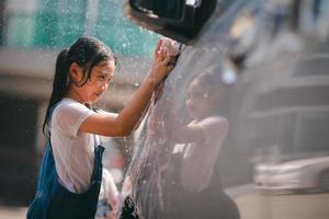 hermano asiático muchachas lavar su carros y tener divertido jugando adentro en un caliente verano día. foto