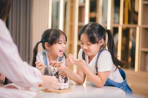 Two children eat a fresh cake together for their birthday photo