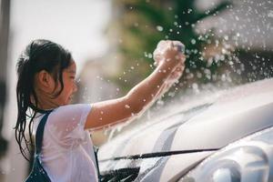 hermano asiático muchachas lavar su carros y tener divertido jugando adentro en un caliente verano día. foto