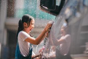 hermano asiático muchachas lavar su carros y tener divertido jugando adentro en un caliente verano día. foto