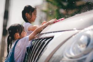 Sibling Asian girls wash their cars and have fun playing indoors on a hot summer day.