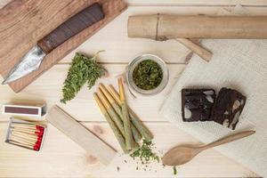 marijuana with drug paraphernalia on wood background photo