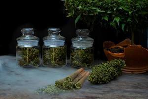 Pre-Roll cannabis joints with cannabis buds in a clear glass jar on the black background photo