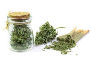 Pre-Roll cannabis joint with cannabis buds in a clear glass jar on the white background photo