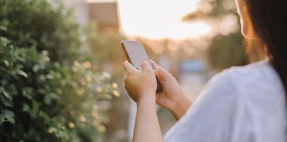 cerca arriba mujer mano sostener utilizando inteligente teléfono en al aire libre parque calle antecedentes. Copiar espacio de tecnología negocio y viaje fiesta concepto. Clásico tono filtrar efecto color estilo. foto