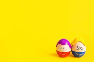 dos huevos divertidos niño y niña con caras sobre un fondo amarillo - pascua, primavera. juguetes para niños: un símbolo de una pareja de hombres y mujeres, amor, familia. copie el espacio foto