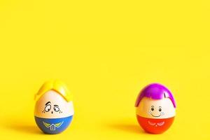 Two eggs with funny faces on yellow background at a distance from each other - Easter, spring. Children's toys-symbol of couple of men and women, love, family, quarrel, breakup, separation. Copy space photo