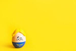 Funny egg toy with a man's sad face on a yellow background. Easter, solitude. Copy space photo