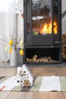 Key to house near fireplace stove with fire and firewood. Cozy home hearth with easter decor, colorful eggs in a basket and bunny. Building, moving, mortgage, rent and purchase real estate, insurance photo