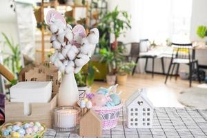 Easter decoration of colorful eggs in a basket and a rabbit on the kitchen table in a rustic style. Festive interior of a country house photo