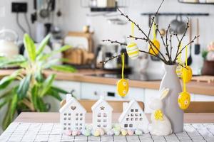 Key to house of cozy home with Easter decor with rabbit and eggs on table of kitchen. Building, design, project, moving to new house, mortgage, insurance, rent and purchase real estate photo